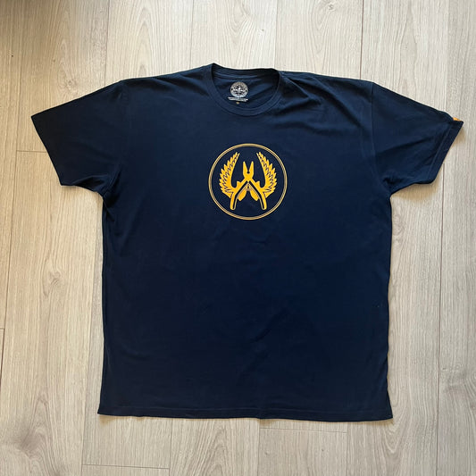 CS:GO 2015 Defuse Kit tee in navy, featuring a bright yellow defuse kit logo on the chest and a small yellow CS:GO patch on the sleeve. Made in Nicaragua from a 60/40 cotton-polyester blend, it includes licensed 2016 Valve Corporation and Counter-Strike Global Offensive tags. A collectible gaming tee that celebrates one of the most iconic in-game items from the series.