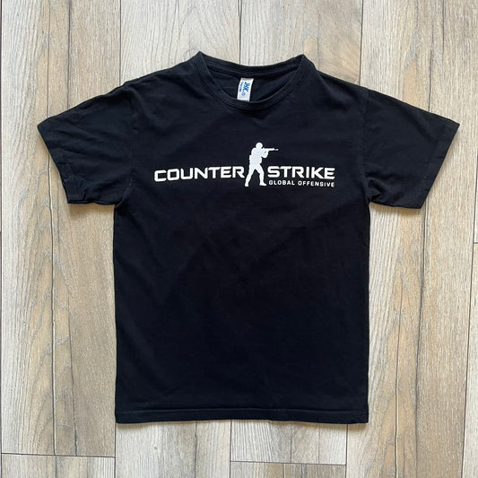 CS:GO Black &amp; White Logo 2010's Tee is a black T-shirt made on a JHK blank. The front features a large white CS:GO logo with an armed figure&nbsp; and “Counter-Strike Global Offensive” text below. Super simple - classic CS logo.