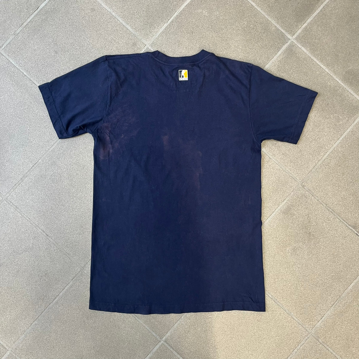 CS:GO Easy Peasy Lemon Squeezy 2015 Tee is a navy T-shirt made in the USA by We Love Fine, featuring a large CS:GO sticker graphic on the front of a hand squeezing a lemon with “Easy Peasy Lemon Squeezy” text. A CS:GO logo is printed on the back below the collar, and it carries a licensed 2015 tag.