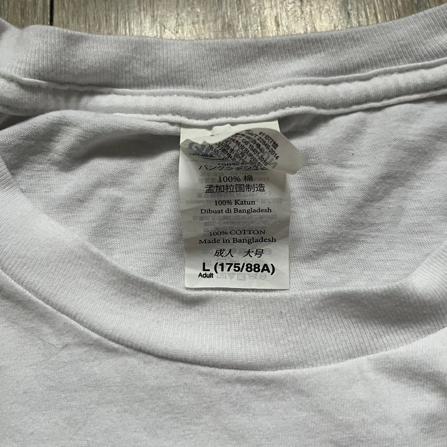 CS:GO White & Red Logo 2010’s Tee is a white T-shirt made from 100% cotton on a Gildan blank. The front features a large red CS:GO logo with an armed figure inside a circle and “Counter-Strike Global Offensive” text below. The shirt reflects early 2010s CS:GO merchandise design.