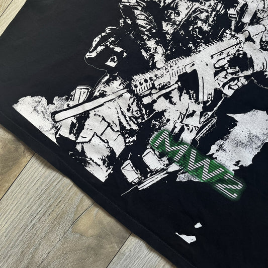 Call of Duty: Modern Warfare 2 2009 Tee is a black T-shirt featuring a large white detailed character with rifle print from the game, under it - green “MW2” text. The sleeve includes an Infinity Ward logo, and the neck tag shows 2009 Activision LVLP branding. Official merchandise from the 2009 Modern Warfare 2 release.