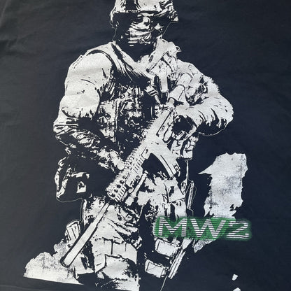 Call of Duty: Modern Warfare 2 2009 Tee is a black T-shirt featuring a large white detailed character with rifle print from the game, under it - green “MW2” text. The sleeve includes an Infinity Ward logo, and the neck tag shows 2009 Activision LVLP branding. Official merchandise from the 2009 Modern Warfare 2 release.