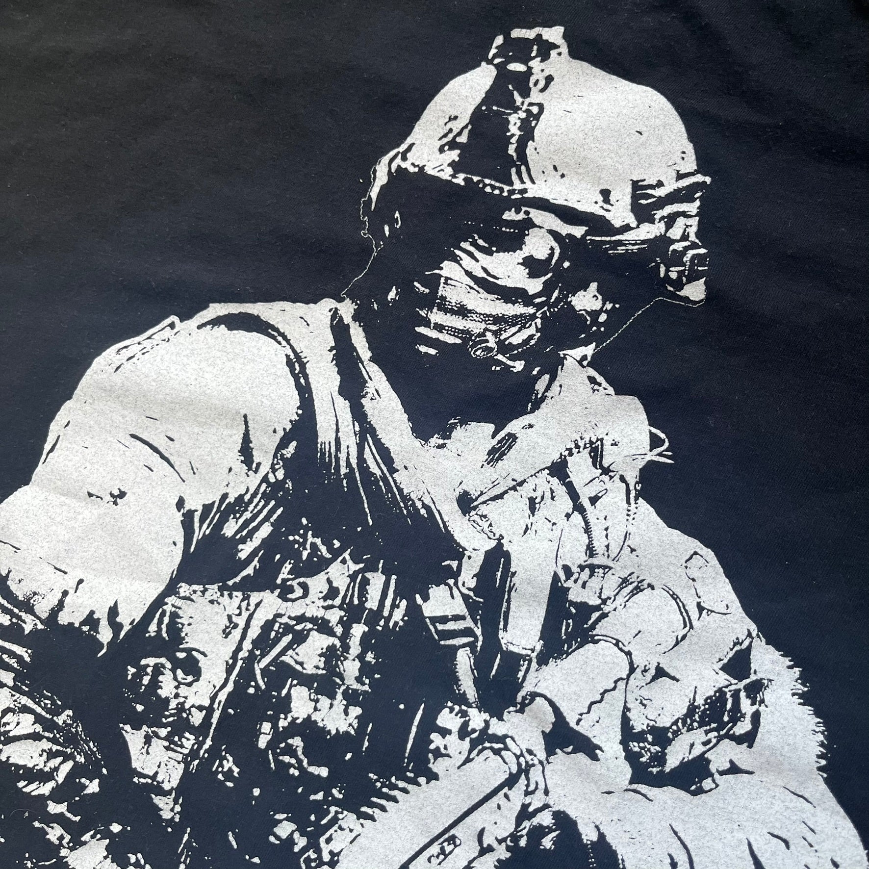 Call of Duty: Modern Warfare 2 2009 Tee is a black T-shirt featuring a large white detailed character with rifle print from the game, under it - green “MW2” text. The sleeve includes an Infinity Ward logo, and the neck tag shows 2009 Activision LVLP branding. Official merchandise from the 2009 Modern Warfare 2 release.