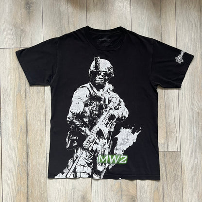Call of Duty: Modern Warfare 2 2009 Tee is a black T-shirt featuring a large white detailed character print from the game with green “MW2” text below. The sleeve includes an Infinity Ward logo, and the neck tag shows 2009 Activision LVLP branding. Official merchandise from the 2009 Modern Warfare 2 release.