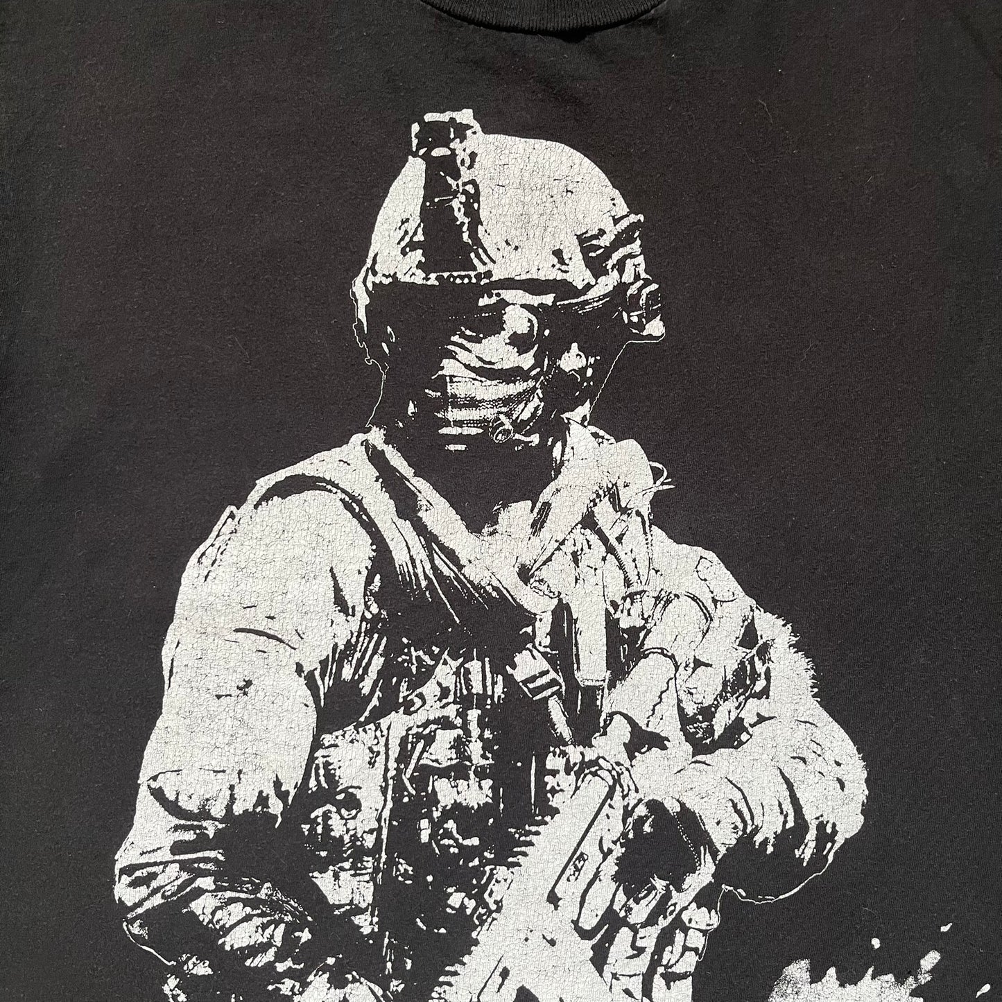 Call of Duty: Modern Warfare 2 2009 Tee is a black T-shirt featuring a large white detailed character print from the game with green “MW2” text below. The sleeve includes an Infinity Ward logo, and the neck tag shows 2009 Activision LVLP branding. Official merchandise from the 2009 Modern Warfare 2 release.