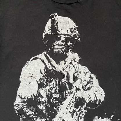 Call of Duty: Modern Warfare 2 2009 Tee is a black T-shirt featuring a large white detailed character print from the game with green “MW2” text below. The sleeve includes an Infinity Ward logo, and the neck tag shows 2009 Activision LVLP branding. Official merchandise from the 2009 Modern Warfare 2 release.