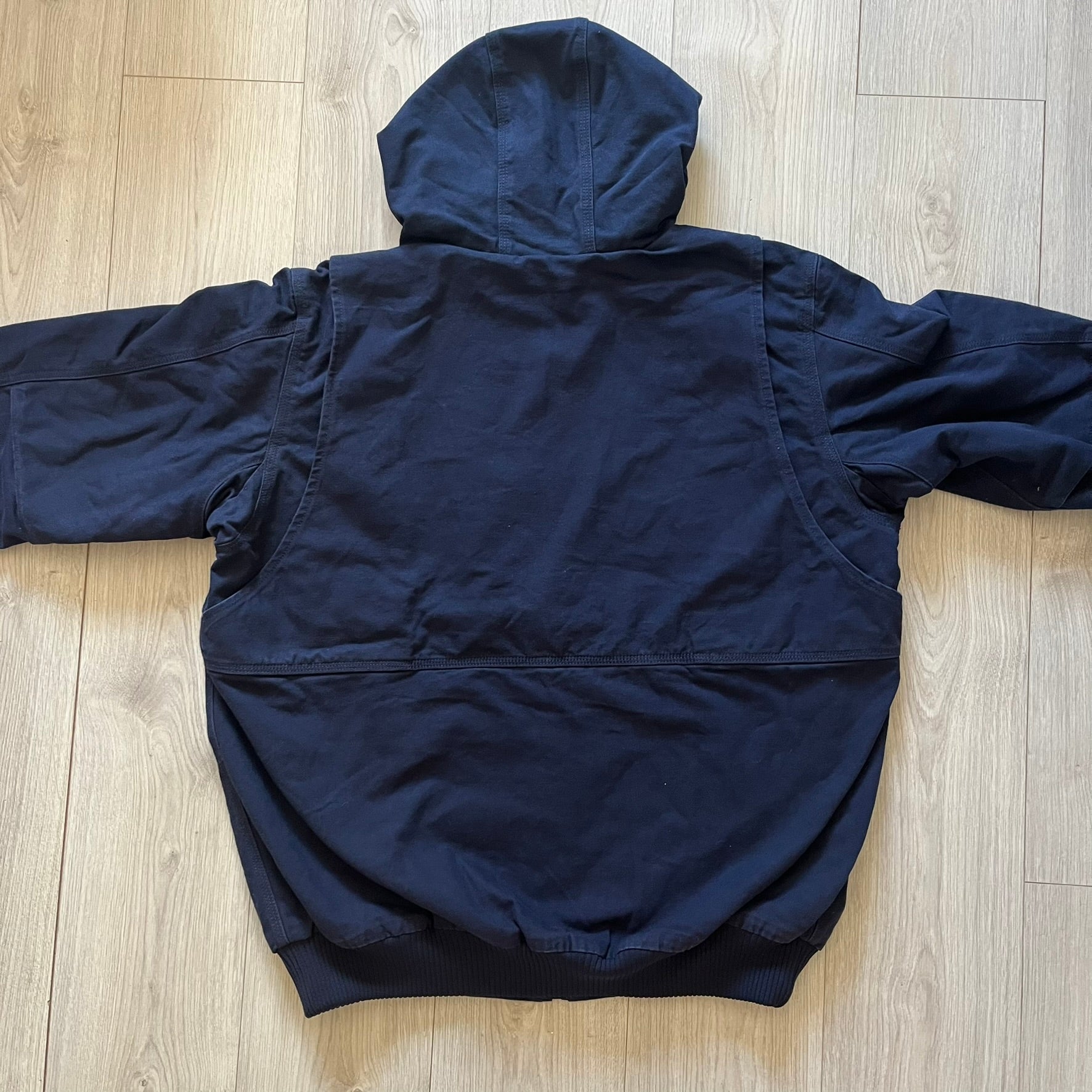 Carhartt Armstrong Full Swing Active Jacket in navy, crafted from heavyweight 12-ounce fleece-lined cotton duck for warmth and durability. Designed with stretch panels across the back and elbows, it allows full range of motion while maintaining a broken-in, comfortable fit. Features include a fleece-lined adjustable hood, rib-knit storm cuffs and waist, triple-stitched main seams, and multiple secure pockets, making it a trusted workwear piece with modernized functionality.