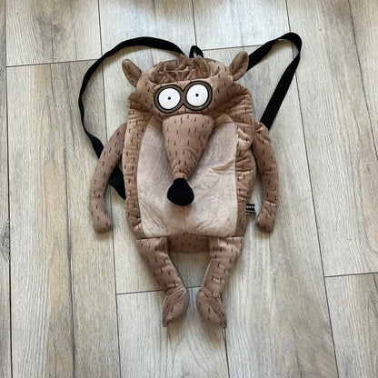 Cartoon Network Regular Show Rigby 2016 Backpack is a character-shaped backpack designed as Rigby from the animated series Regular Show. The bag features a full plush body construction with movable arms, legs, and mouth, while the eyes and mouth are finished with embroidered detailing. Adjustable straps are attached from the top to the lower back of the character, allowing it to be worn as a standard backpack. The design follows Rigby’s appearance with brown fur tones, dark raccoon-style eye mask markings, 