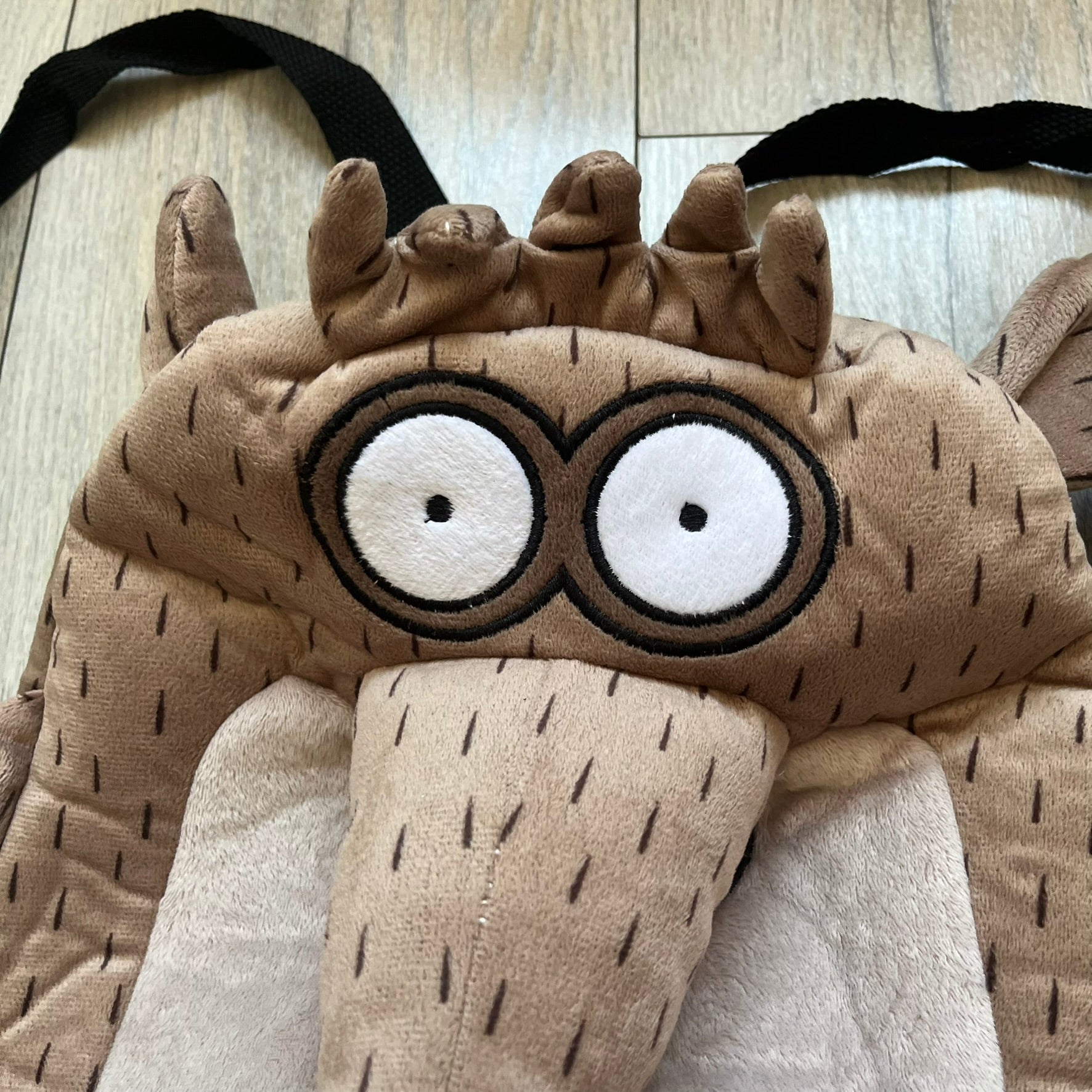 Cartoon Network Regular Show Rigby 2016 Backpack is a character-shaped backpack designed as Rigby from the animated series Regular Show. The bag features a full plush body construction with movable arms, legs, and mouth, while the eyes and mouth are finished with embroidered detailing. Adjustable straps are attached from the top to the lower back of the character, allowing it to be worn as a standard backpack. The design follows Rigby’s appearance with brown fur tones, dark raccoon-style eye mask markings, 