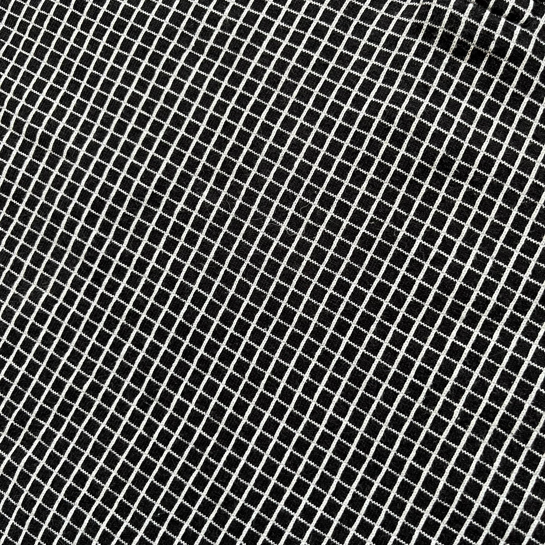 Cartoon Network Scooby-Doo 1999 Golf Polo is a black polo shirt featuring a grid pattern of thin white lines forming small squares across the fabric. The left chest displays an embroidered graphic of Scooby-Doo in a golf outfit digging in sand. The neck tag includes Warner Bros. and Cartoon Network 1999 licensing.