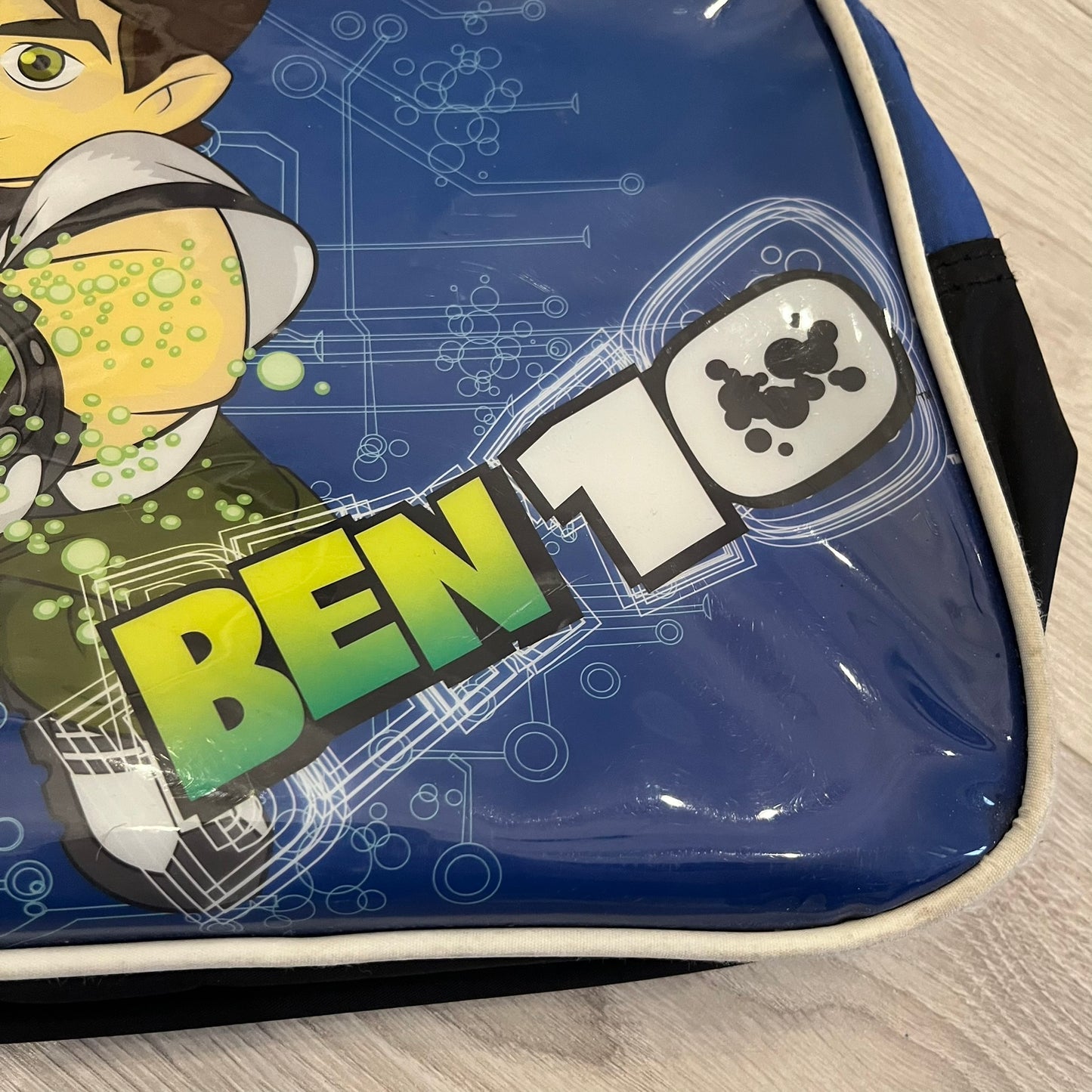 Blue Cartoon Network “Ben 10” handbag with black straps. Features a front graphic of Ben 10 with several of his evolve forms and the Ben 10 logo on the bottom right. Includes an internal Cartoon Network tag marked S10 for the 2010 season.