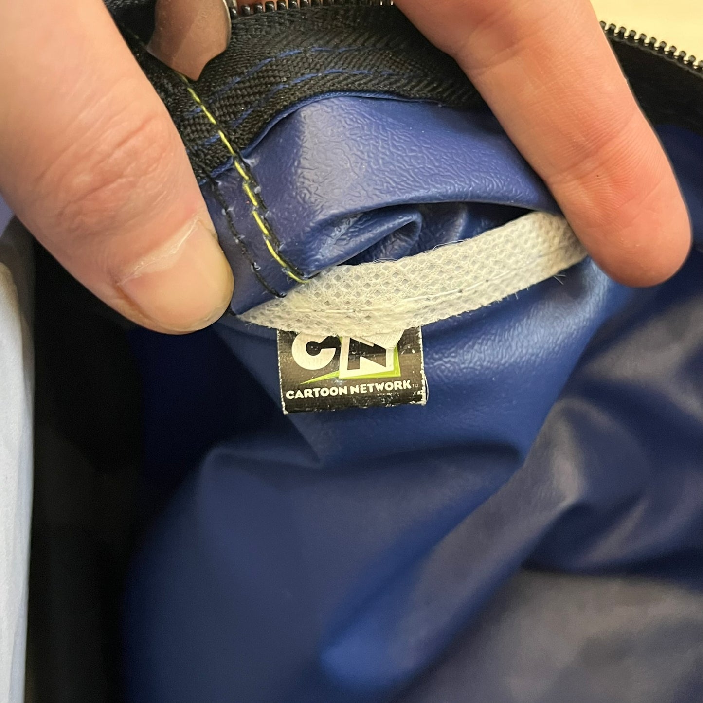 Blue Cartoon Network “Ben 10” handbag with black straps. Features a front graphic of Ben 10 with several of his evolve forms and the Ben 10 logo on the bottom right. Includes an internal Cartoon Network tag marked S10 for the 2010 season.