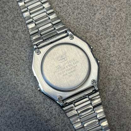 Custom Casio A158 "Double Holo" Silver Digital Watch (A158WEA-7EF) is a custom Casio digital watch with a Double Holo (Stars and normal holo) filter over the square resin glass screen and a stainless steel band with an adjustable clasp, compatible with wrist sizes from 150 to 205 mm. It has a 1/100-second stopwatch, a daily alarm, an hourly time signal, an auto-calendar, a 12/24-hour format, a green LED light, and water resistance.