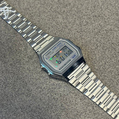 Custom Casio A158 "Double Holo" Silver Digital Watch (A158WEA-7EF) is a custom Casio digital watch with a Double Holo (Stars and normal holo) filter over the square resin glass screen and a stainless steel band with an adjustable clasp, compatible with wrist sizes from 150 to 205 mm. It has a 1/100-second stopwatch, a daily alarm, an hourly time signal, an auto-calendar, a 12/24-hour format, a green LED light, and water resistance.