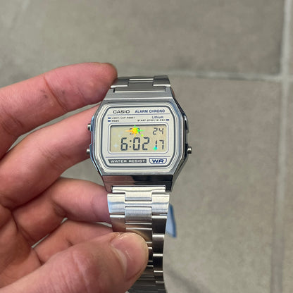 Custom Casio A158 "Double Holo" Silver Digital Watch (A158WEA-7EF) is a custom Casio digital watch with a Double Holo (Stars and normal holo) filter over the square resin glass screen and a stainless steel band with an adjustable clasp, compatible with wrist sizes from 150 to 205 mm. It has a 1/100-second stopwatch, a daily alarm, an hourly time signal, an auto-calendar, a 12/24-hour format, a green LED light, and water resistance.