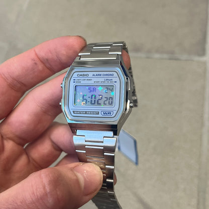 Custom Casio A158 "Double Holo" Silver Digital Watch (A158WEA-7EF) is a custom Casio digital watch with a Double Holo (Stars and normal holo) filter over the square resin glass screen and a stainless steel band with an adjustable clasp, compatible with wrist sizes from 150 to 205 mm. It has a 1/100-second stopwatch, a daily alarm, an hourly time signal, an auto-calendar, a 12/24-hour format, a green LED light, and water resistance.