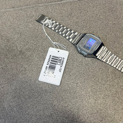 Custom Casio A158 "Double Holo" Silver Digital Watch (A158WEA-7EF) is a custom Casio digital watch with a Double Holo (Stars and normal holo) filter over the square resin glass screen and a stainless steel band with an adjustable clasp, compatible with wrist sizes from 150 to 205 mm. It has a 1/100-second stopwatch, a daily alarm, an hourly time signal, an auto-calendar, a 12/24-hour format, a green LED light, and water resistance.