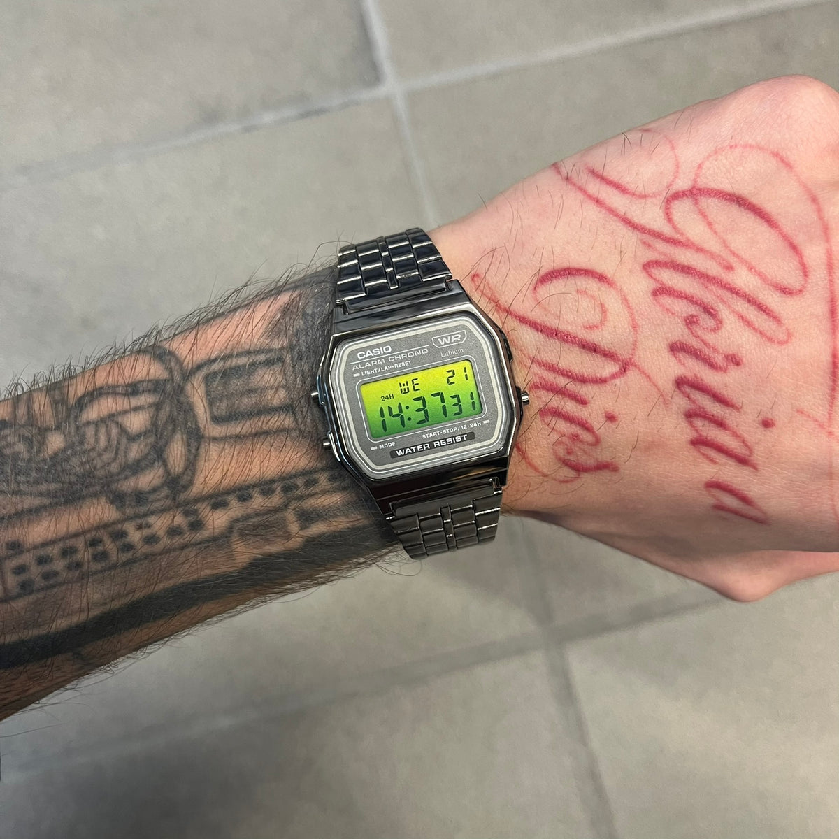 Custom Casio A158 “Emerald” Green &amp; Black Digital Watch is a watch with a green gradient filter over the square screen and a grey ion-plated stainless steel band with an adjustable clasp. The case comes with a resin glass and a resin and black chrome-plated case and bezel. It has a 1/100-second stopwatch, a daily alarm, an hourly time signal, an auto-calendar, a 12/24-hour format, a green LED light, and water resistance.