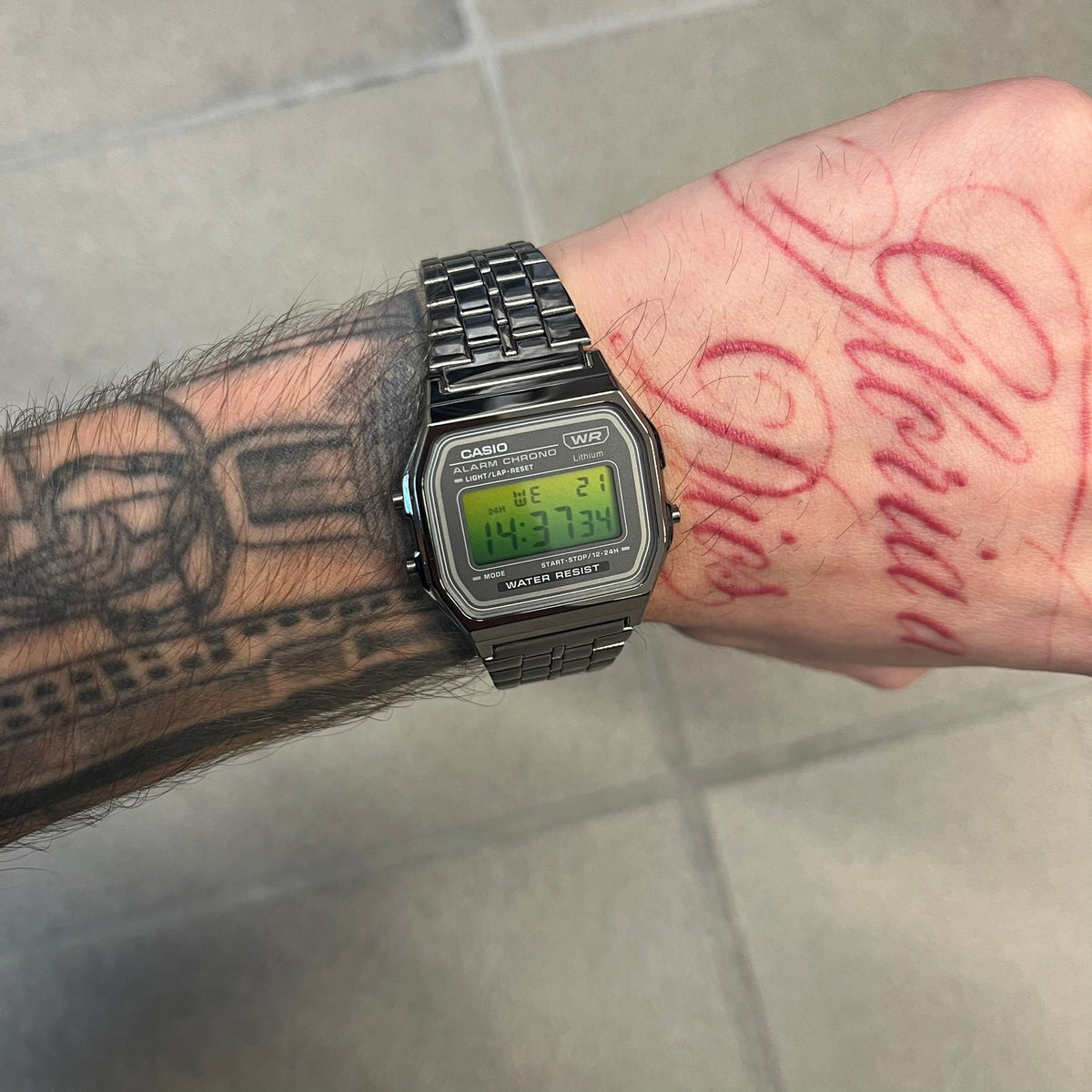 Custom Casio A158 “Emerald” Green &amp; Black Digital Watch is a watch with a green gradient filter over the square screen and a grey ion-plated stainless steel band with an adjustable clasp. The case comes with a resin glass and a resin and black chrome-plated case and bezel. It has a 1/100-second stopwatch, a daily alarm, an hourly time signal, an auto-calendar, a 12/24-hour format, a green LED light, and water resistance.