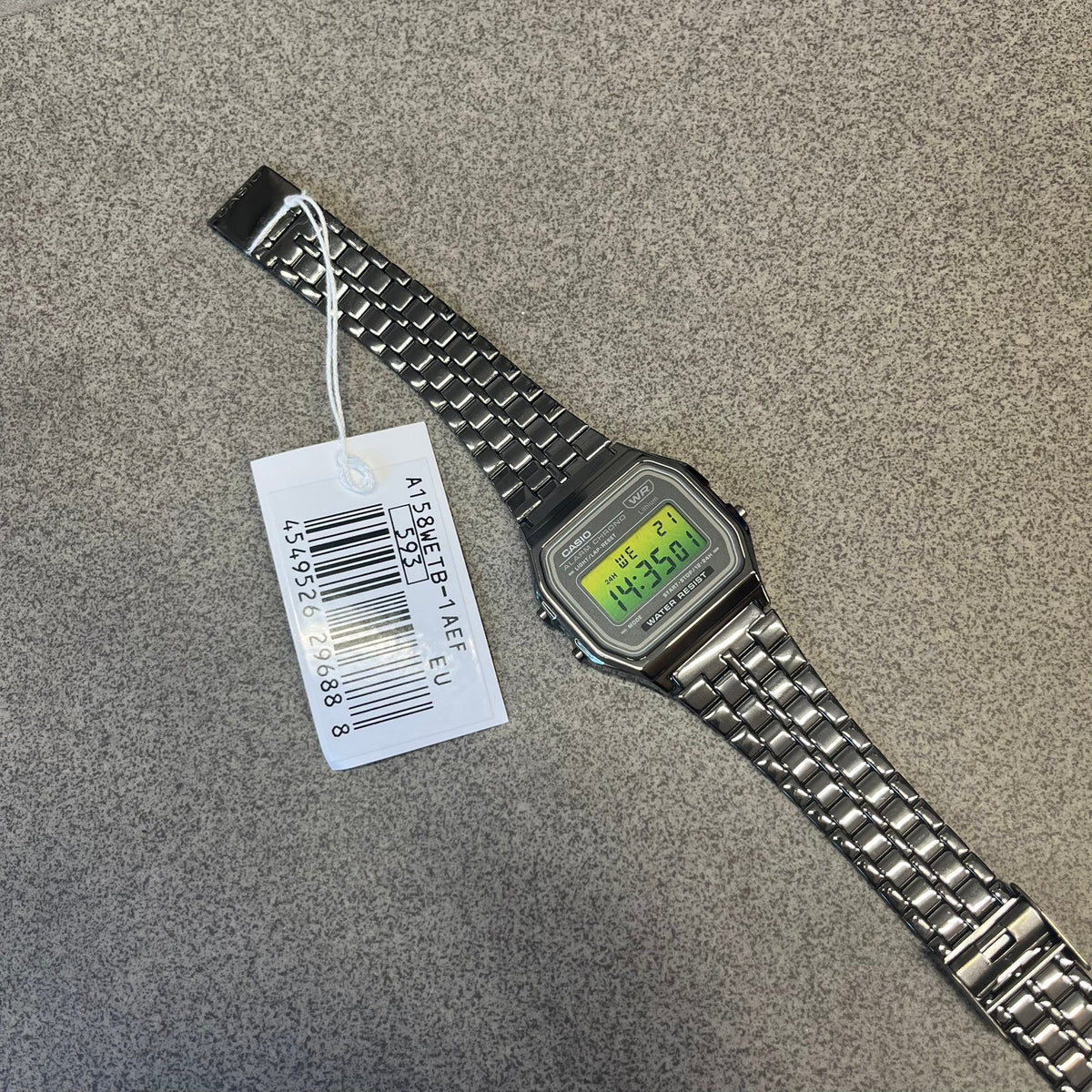 Custom Casio A158 “Emerald” Green &amp; Black Digital Watch is a watch with a green gradient filter over the square screen and a grey ion-plated stainless steel band with an adjustable clasp. The case comes with a resin glass and a resin and black chrome-plated case and bezel. It has a 1/100-second stopwatch, a daily alarm, an hourly time signal, an auto-calendar, a 12/24-hour format, a green LED light, and water resistance.