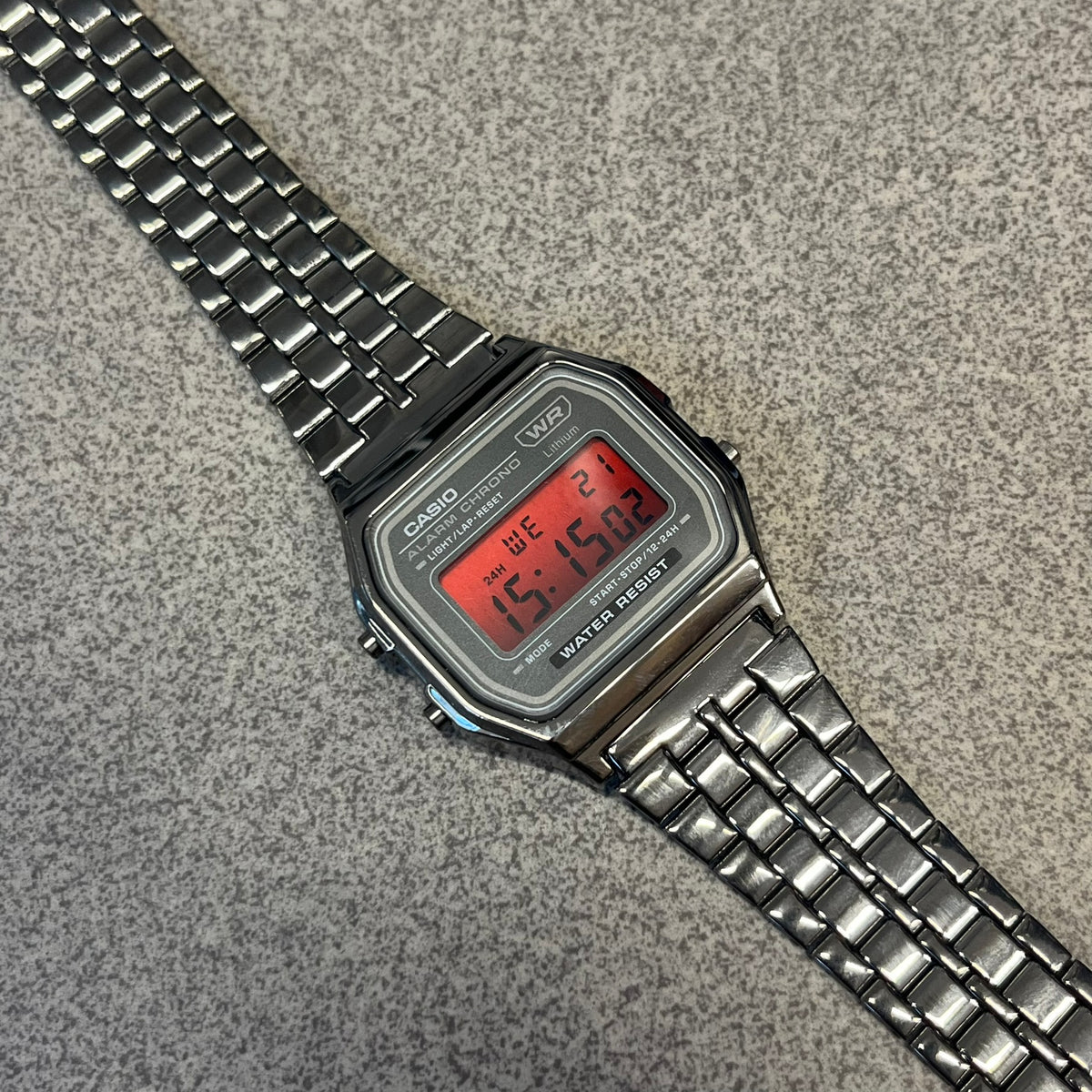 Custom Casio A158 "Red Moon" Black &amp; Red Digital Watch is a watch with a red gradient filter over the square screen and a grey ion-plated stainless steel band with an adjustable clasp. The case comes with a resin glass and a resin and black chrome-plated case and bezel. It has a 1/100-second stopwatch, a daily alarm, an hourly time signal, an auto-calendar, a 12/24-hour format, a green LED light, and water resistance.