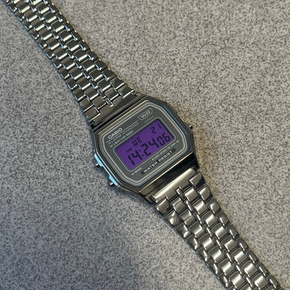 Custom Casio A158 "Royal Purple" Black &amp; Purple Digital Watch is a watch with a purple filter over the square screen and a grey ion-plated stainless steel band with an adjustable clasp. The case comes with a resin glass and a resin and black chrome-plated case and bezel. It has a 1/100-second stopwatch, a daily alarm, an hourly time signal, an auto-calendar, a 12/24-hour format, a green LED light, and water resistance.