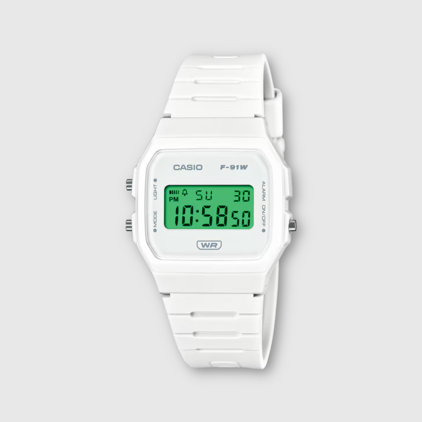 White Casio digital watch with green display on a light gray background