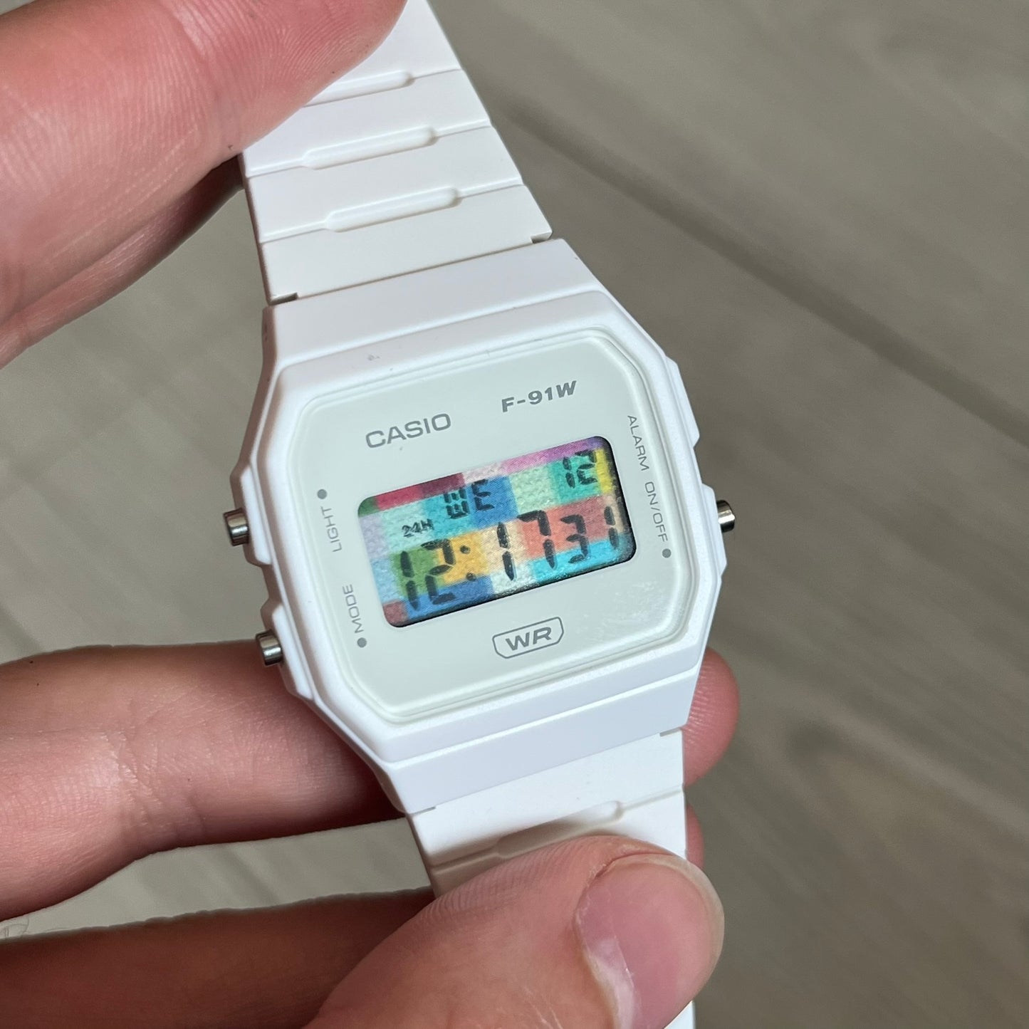 Custom Casio F-91W White digital watch featuring a Multicolor interlocking bricks filter screen. Slim 8.5 mm profile, lightweight 21 g build and flexible bio-based resin band ensure lasting comfort. Includes alarm, stopwatch, and microlight function for everyday functionality.