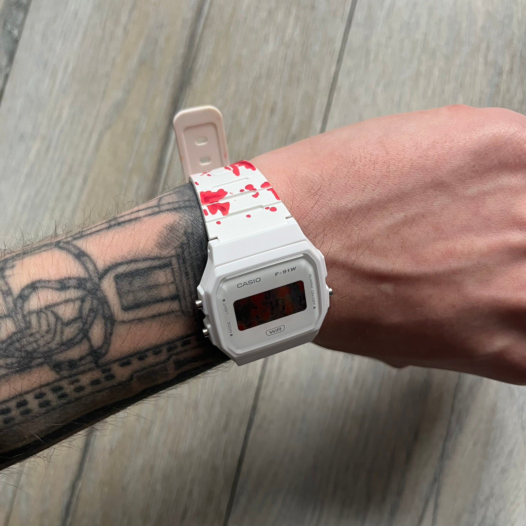 Custom Casio F-91W White digital watch featuring a Bloody filter screen and custom painted straps. Slim 8.5 mm profile, lightweight 21 g build and flexible bio-based resin band ensure lasting comfort. Includes alarm, stopwatch, and microlight function for everyday functionality.

This watch is a 1/1 sample. The paint on the straps is not holding perfectly as with more force it can be smudged. For the best effect we reccomend covering it with a special paint or spray to make it 100% last.&nbsp;