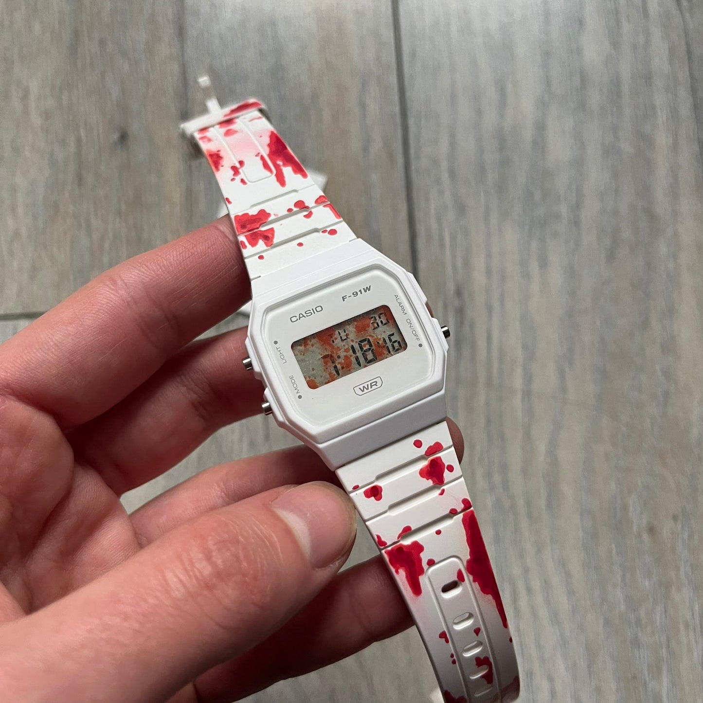 Custom Casio F-91W White digital watch featuring a Bloody filter screen and custom painted straps. Slim 8.5 mm profile, lightweight 21 g build and flexible bio-based resin band ensure lasting comfort. Includes alarm, stopwatch, and microlight function for everyday functionality.

This watch is a 1/1 sample. The paint on the straps is not holding perfectly as with more force it can be smudged. For the best effect we reccomend covering it with a special paint or spray to make it 100% last.&nbsp;