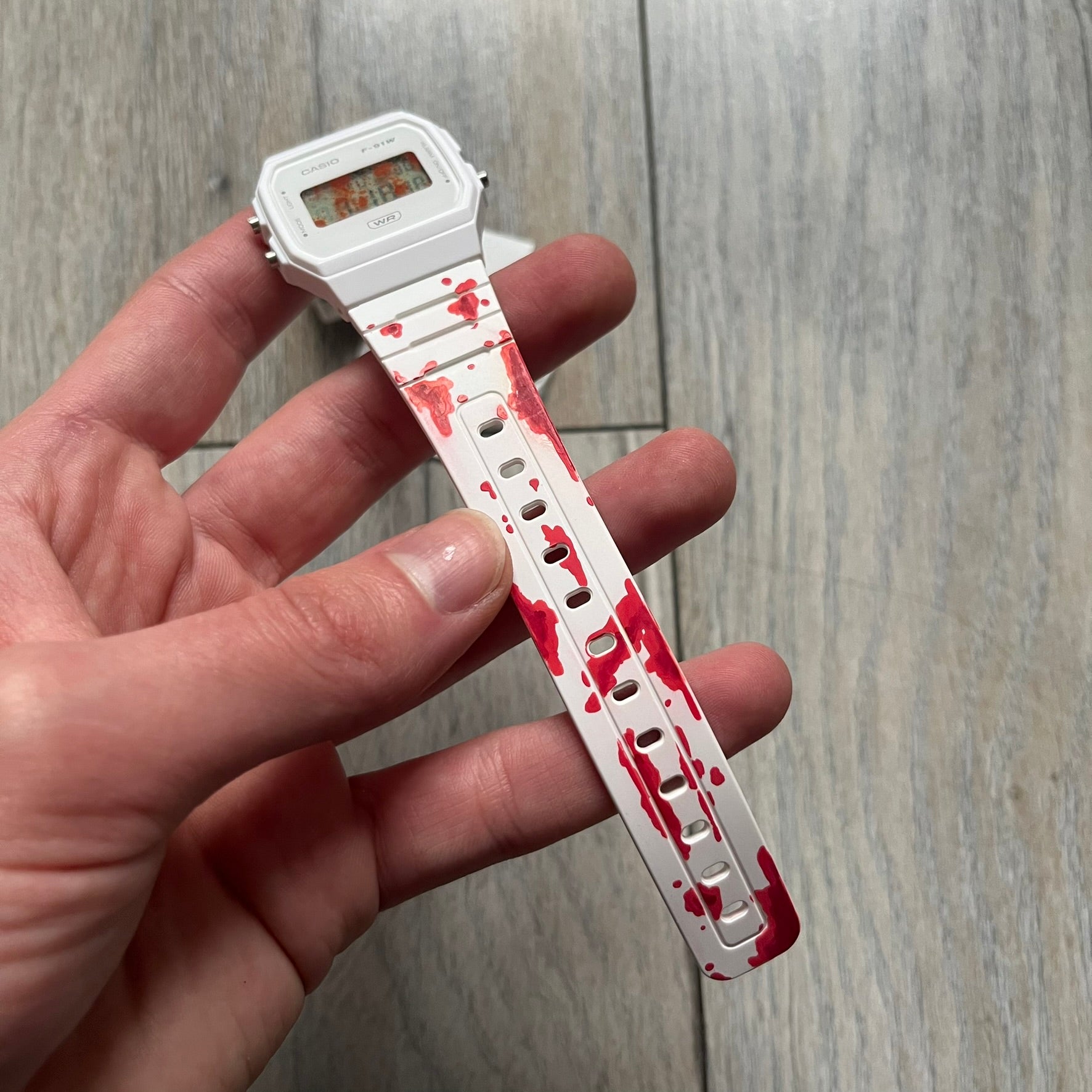 Custom Casio F-91W White digital watch featuring a Bloody filter screen and custom painted straps. Slim 8.5 mm profile, lightweight 21 g build and flexible bio-based resin band ensure lasting comfort. Includes alarm, stopwatch, and microlight function for everyday functionality.

This watch is a 1/1 sample. The paint on the straps is not holding perfectly as with more force it can be smudged. For the best effect we reccomend covering it with a special paint or spray to make it 100% last.&nbsp;