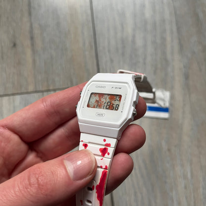 Custom Casio F-91W White digital watch featuring a Bloody filter screen and custom painted straps. Slim 8.5 mm profile, lightweight 21 g build and flexible bio-based resin band ensure lasting comfort. Includes alarm, stopwatch, and microlight function for everyday functionality.

This watch is a 1/1 sample. The paint on the straps is not holding perfectly as with more force it can be smudged. For the best effect we reccomend covering it with a special paint or spray to make it 100% last.&nbsp;