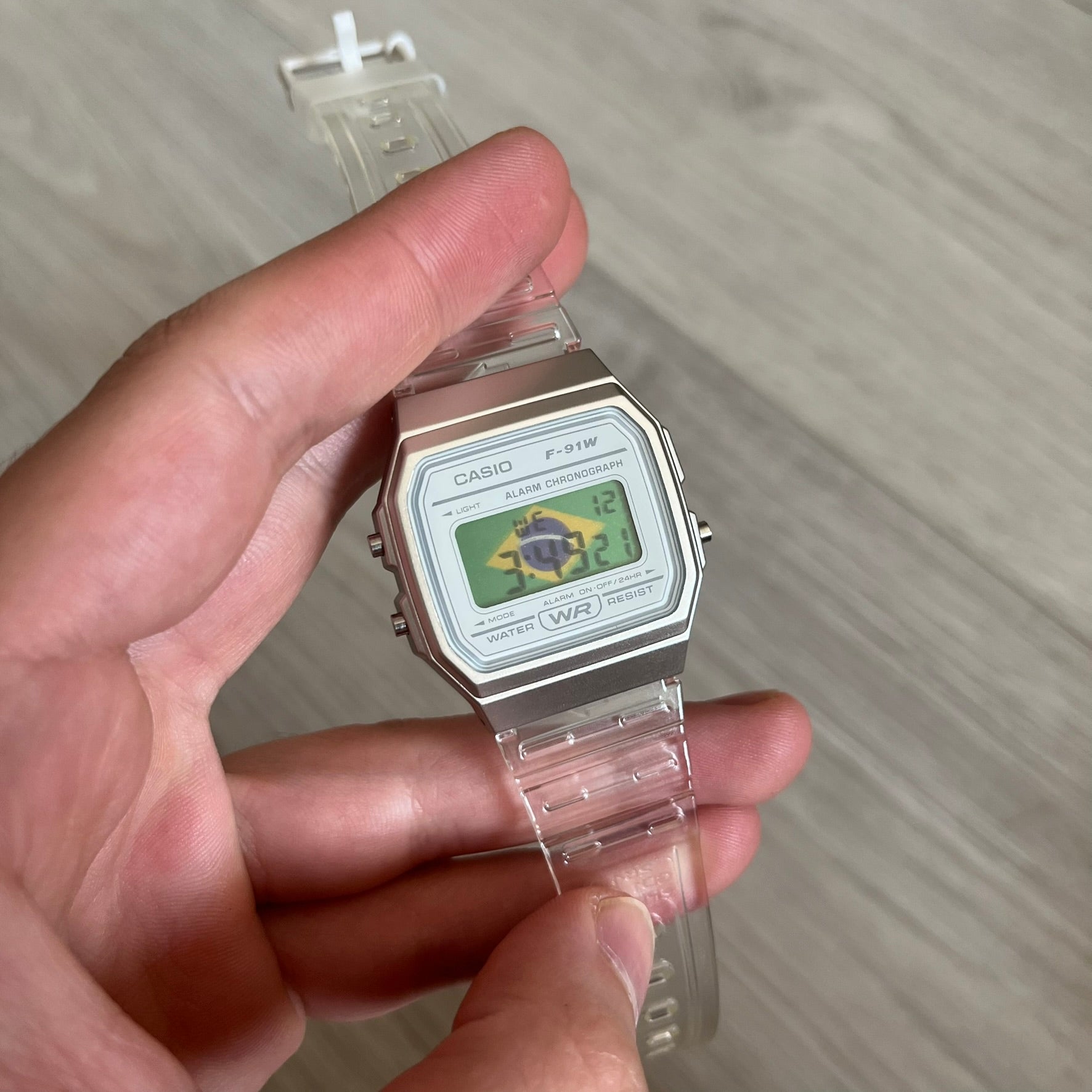 Custom Casio F-91W Clear/Transparent digital watch featuring a Brazil Flag filter screen. Slim 8.5 mm profile, lightweight 21 g build and flexible bio-based resin band ensure lasting comfort. Includes alarm, stopwatch, and microlight function for everyday functionality.