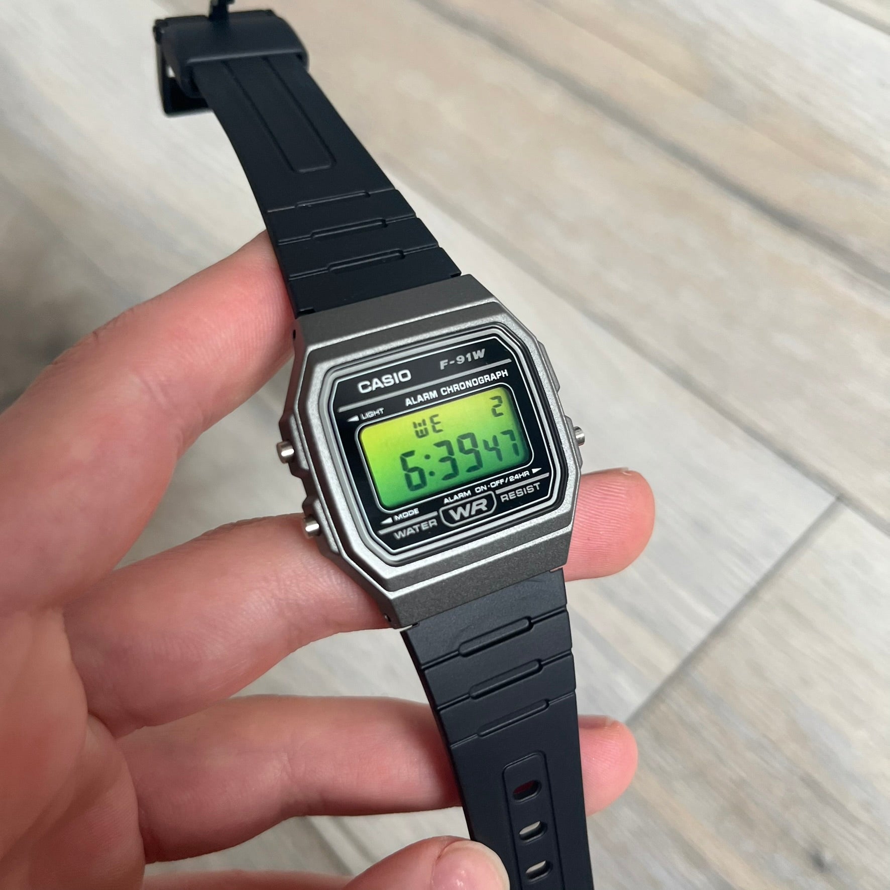 Custom Casio F-91W Black and silver digital watch featuring a Green gradient filter screen. Slim 8.5 mm profile, lightweight 21 g build and flexible bio-based resin band ensure lasting comfort. Includes alarm, stopwatch, and microlight function for everyday functionality.