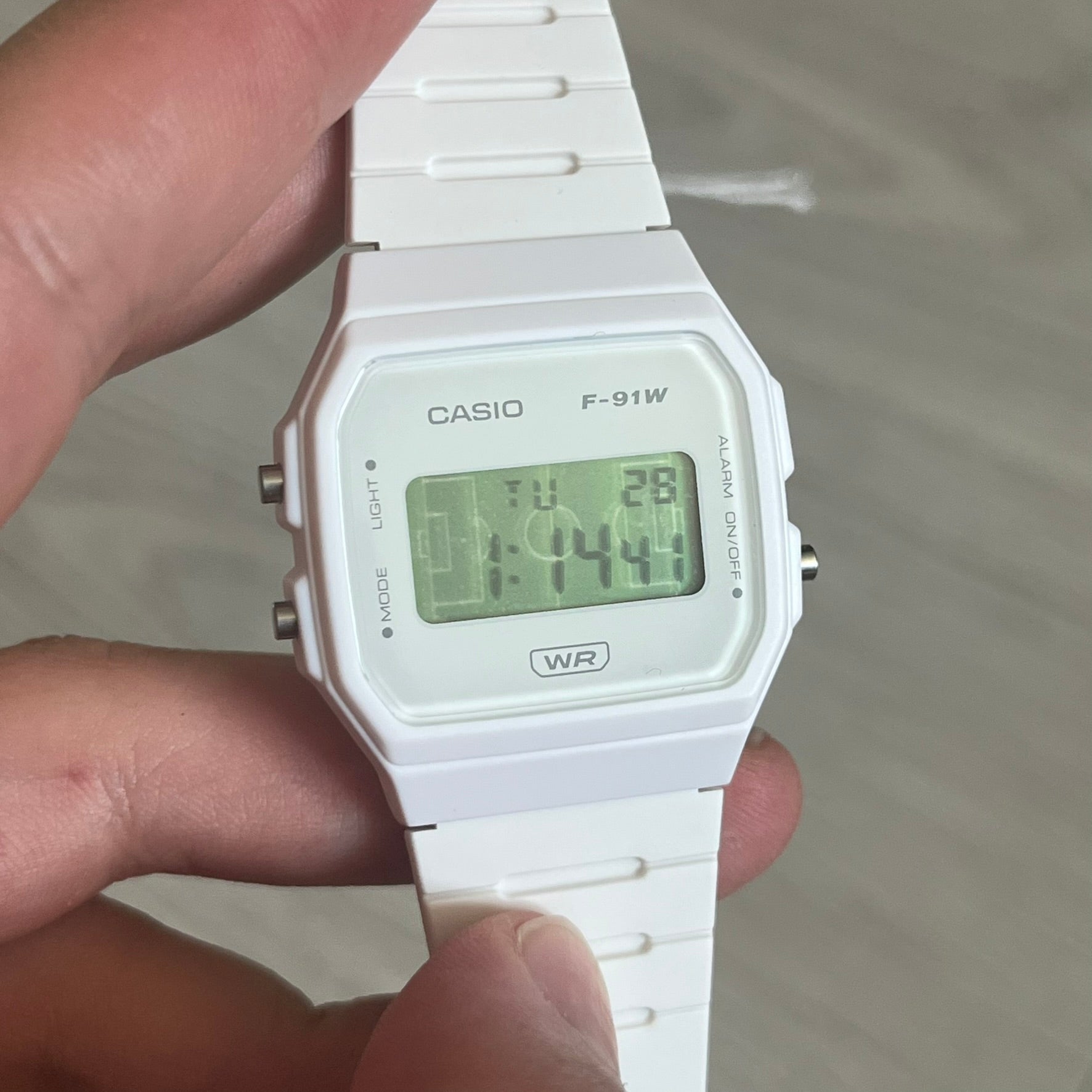 Custom Casio F-91W White digital watch featuring a Green Football Pitch filter screen. Slim 8.5 mm profile, lightweight 21 g build and flexible bio-based resin band ensure lasting comfort. Includes alarm, stopwatch, and microlight function for everyday functionality.
