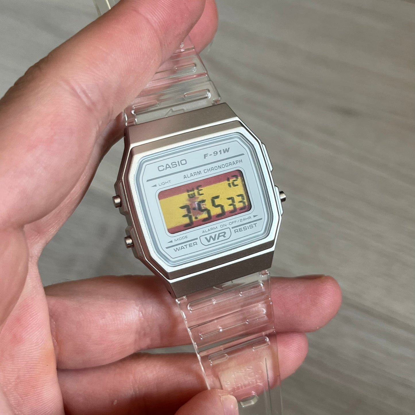 Custom Casio F-91W Clear/Transparent digital watch featuring a Spanish Flag filter screen. Slim 8.5 mm profile, lightweight 21 g build and flexible bio-based resin band ensure lasting comfort. Includes alarm, stopwatch, and microlight function for everyday functionality.