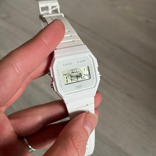 Custom Casio F-91W White digital watch featuring a Trollface meme filter screen. Slim 8.5 mm profile, lightweight 21 g build and flexible bio-based resin band ensure lasting comfort. Includes alarm, stopwatch, and microlight function for everyday functionality.