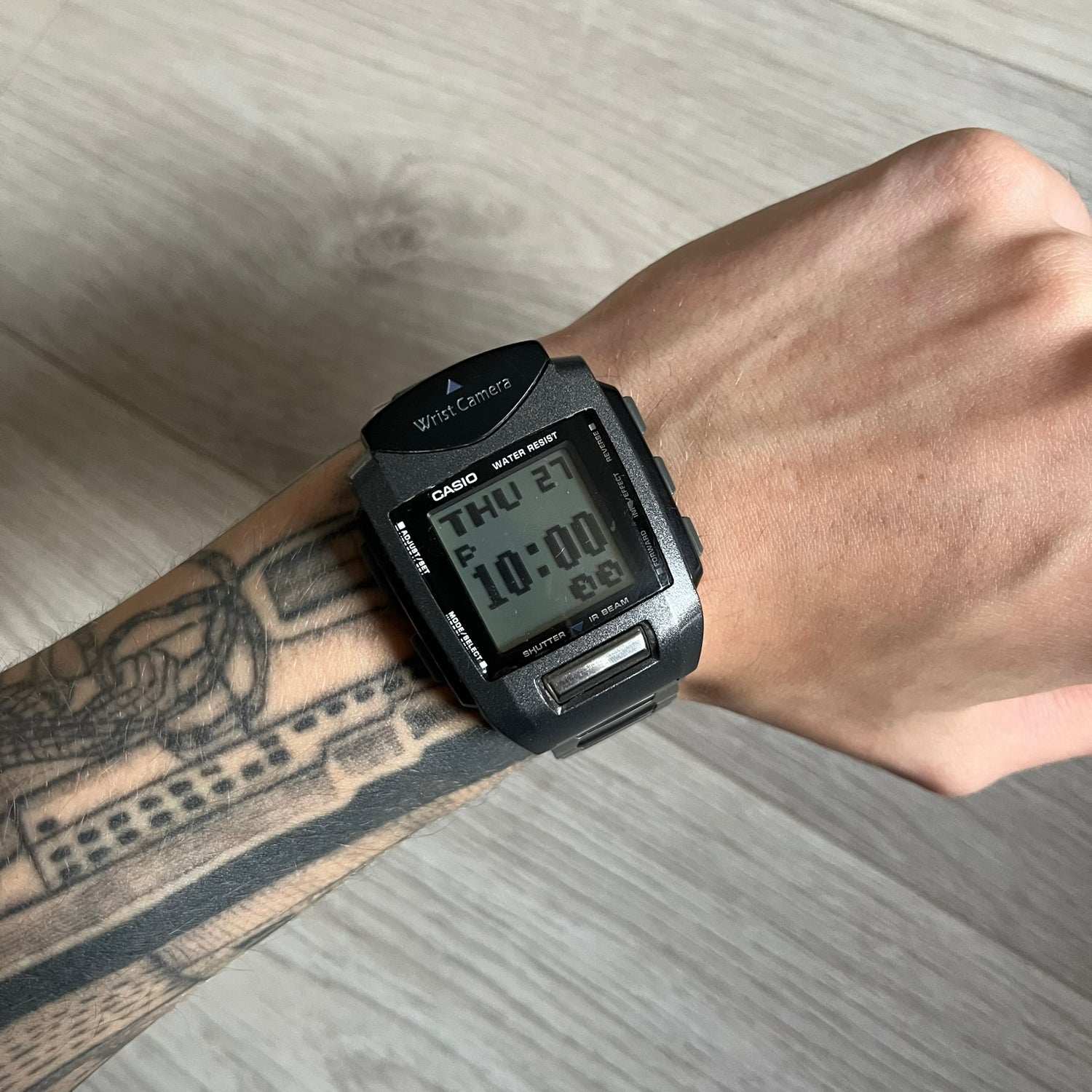 Casio Wrist Camera 2220 WQV-1 Digital Watch from the 2000s, made in Japan. Features a built-in camera module at the top, with six function buttons for photo capture, IR communication, alarm, timer, stopwatch, and gallery viewing. Monochrome photo output in shades of black, white, and gray; fitted with a non-original bracelet.