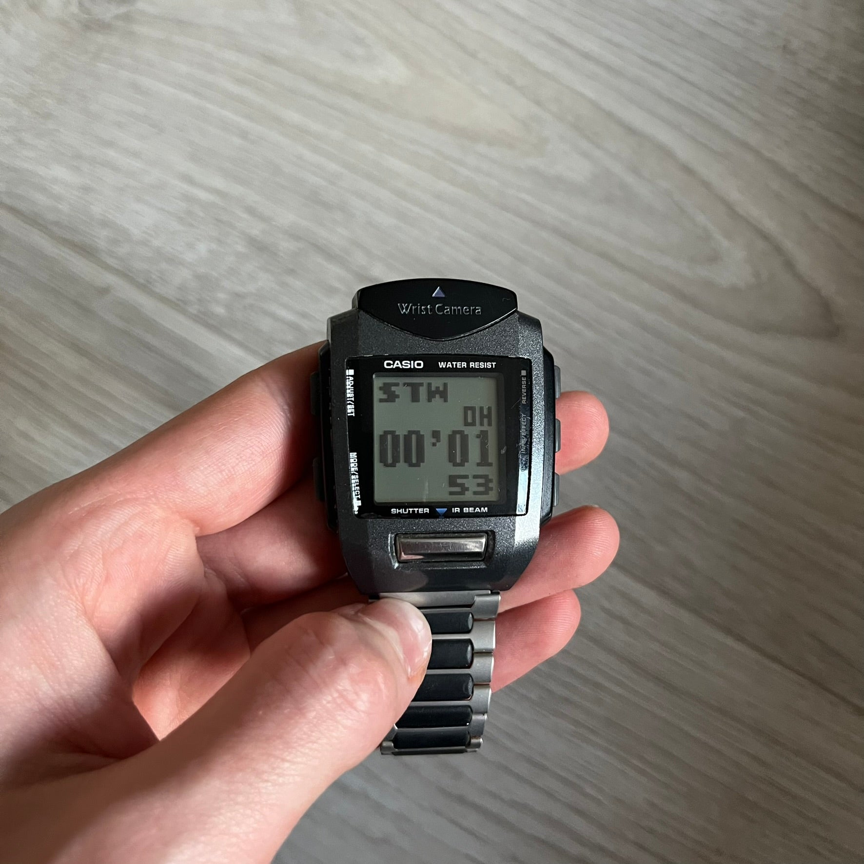 Casio Wrist Camera 2220 WQV-1 Digital Watch from the 2000s, made in Japan. Features a built-in camera module at the top, with six function buttons for photo capture, IR communication, alarm, timer, stopwatch, and gallery viewing. Monochrome photo output in shades of black, white, and gray; fitted with a non-original bracelet.