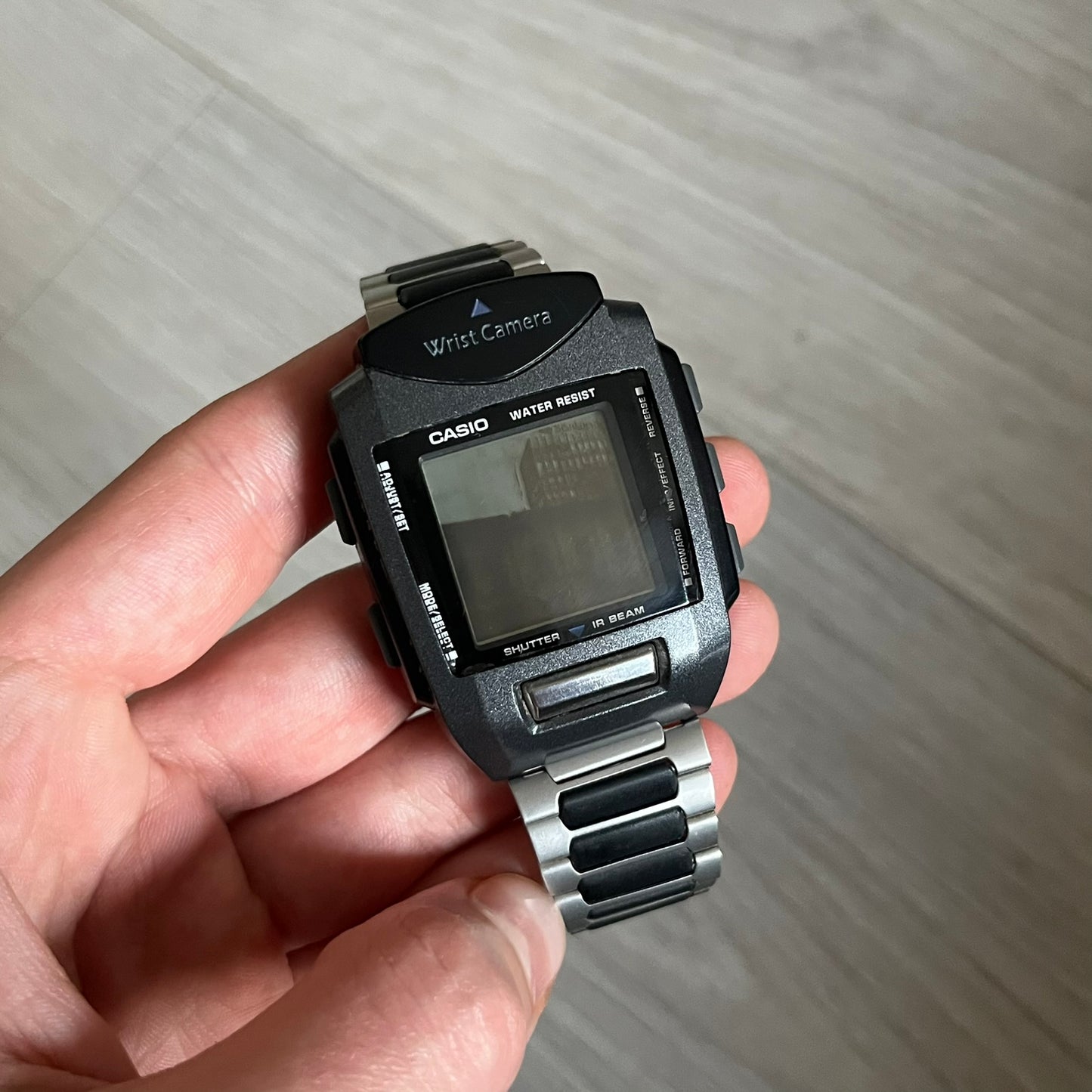 Casio Wrist Camera 2220 WQV-1 Digital Watch from the 2000s, made in Japan. Features a built-in camera module at the top, with six function buttons for photo capture, IR communication, alarm, timer, stopwatch, and gallery viewing. Monochrome photo output in shades of black, white, and gray; fitted with a non-original bracelet.