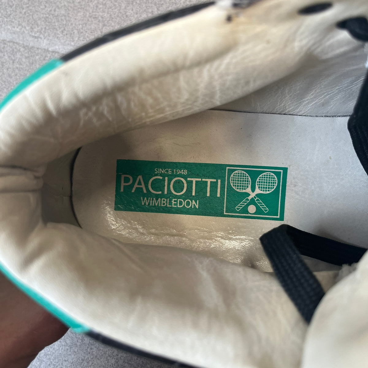 Cesare Paciotti Wimbledon Cocco Lux Black Sneakers (CPM5121) are made in Italy from black crocodile-embossed leather, with a Paciotti Wimbledon tag showing two rackets on the tongue and a second logo on the heel. The white rubber sole has a textured zipper-teeth detail running around its edge. They come with the original box, which shows wear.