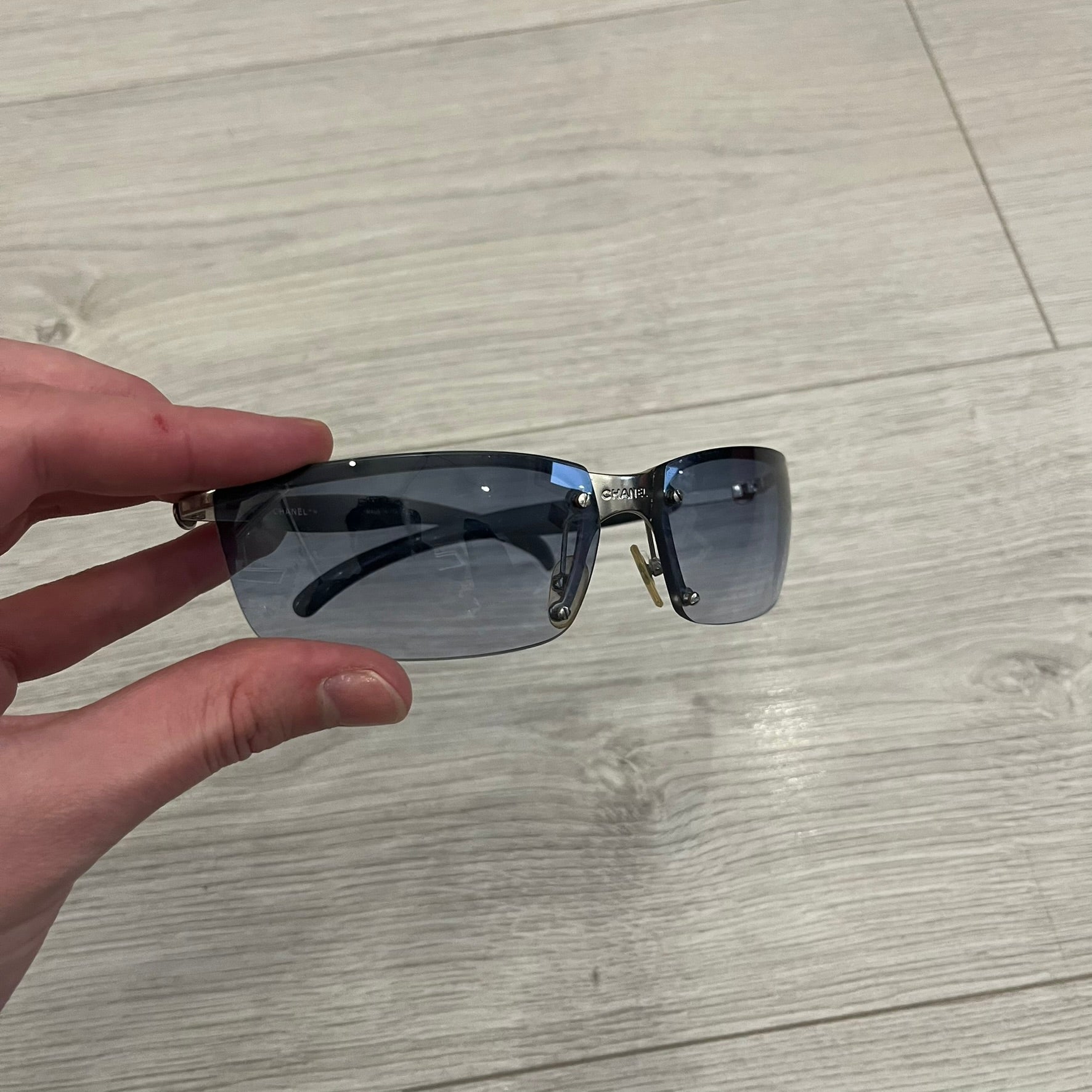 Chanel 4008 Rimless Silver Sunglasses with blue gradient lenses, combining a futuristic rimless design with vintage early 2000s style. Features CC logos on the temples, Chanel engraving on the bridge, and a silver metal frame. Made in Italy with CE certification.
