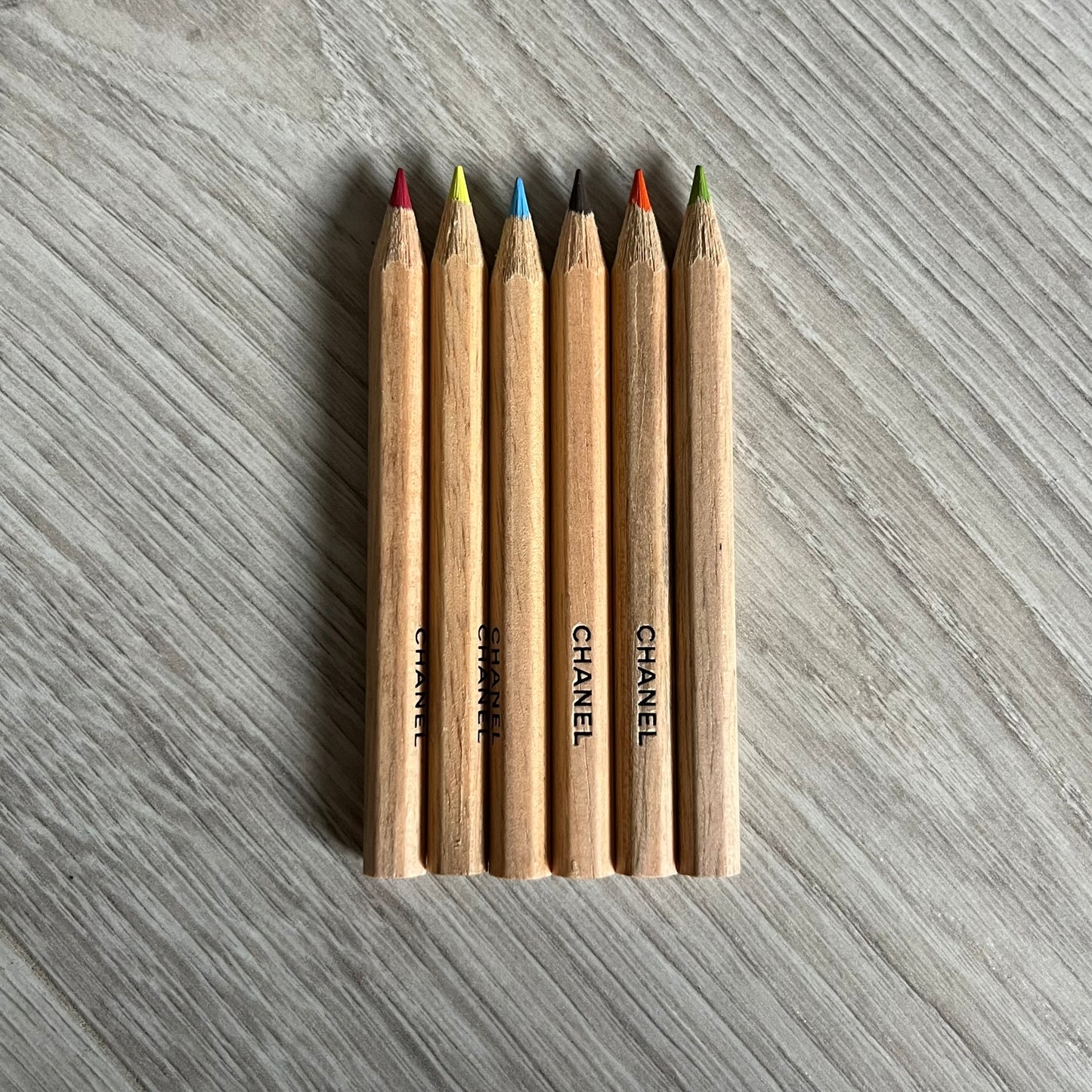 Chanel Mother’s Day Colored Pencils Set from 2021, presented in a white cylindrical tube with “Happy Mother’s Day” text and the Chanel logo on top. A Chanel Beauté complimentary gift featuring six branded colored pencils in blue, red, yellow, brown, orange, and green.