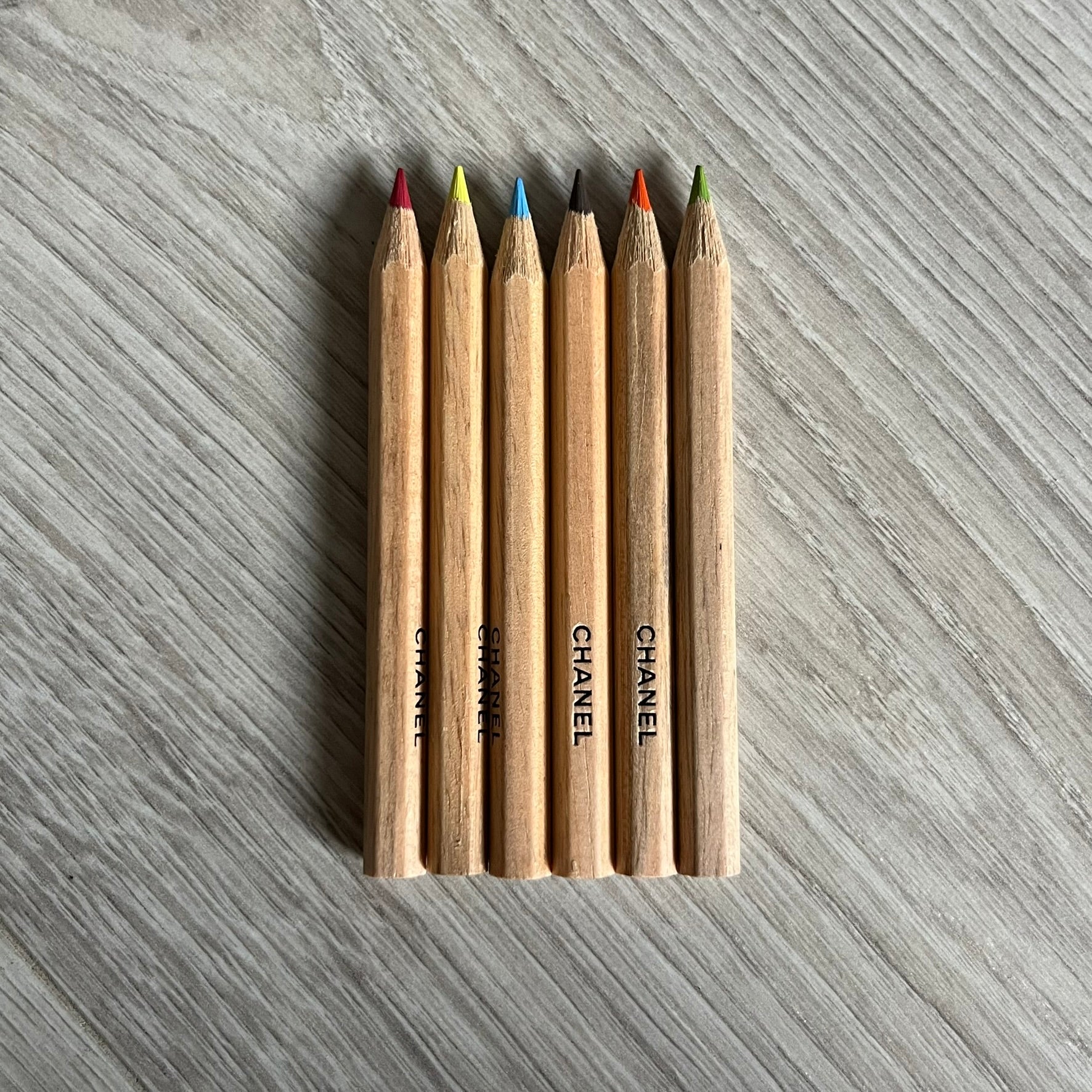 Chanel Mother’s Day Colored Pencils Set from 2021, presented in a white cylindrical tube with “Happy Mother’s Day” text and the Chanel logo on top. A Chanel Beauté complimentary gift featuring six branded colored pencils in blue, red, yellow, brown, orange, and green.