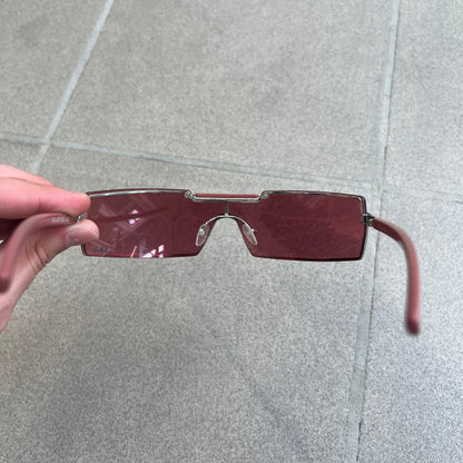 Christian Dior Viktim 2 Pink Sunglasses are an early 2000's eyewear piece from the Safilo era, featuring a futuristic rimless shield silhouette with a sleek wraparound lens design. The sunglasses have a pink/rose tinted lens with subtle Dior logo details at the bottom and minimalist framing. Made in Austria, they come complete with a silver Dior case.
