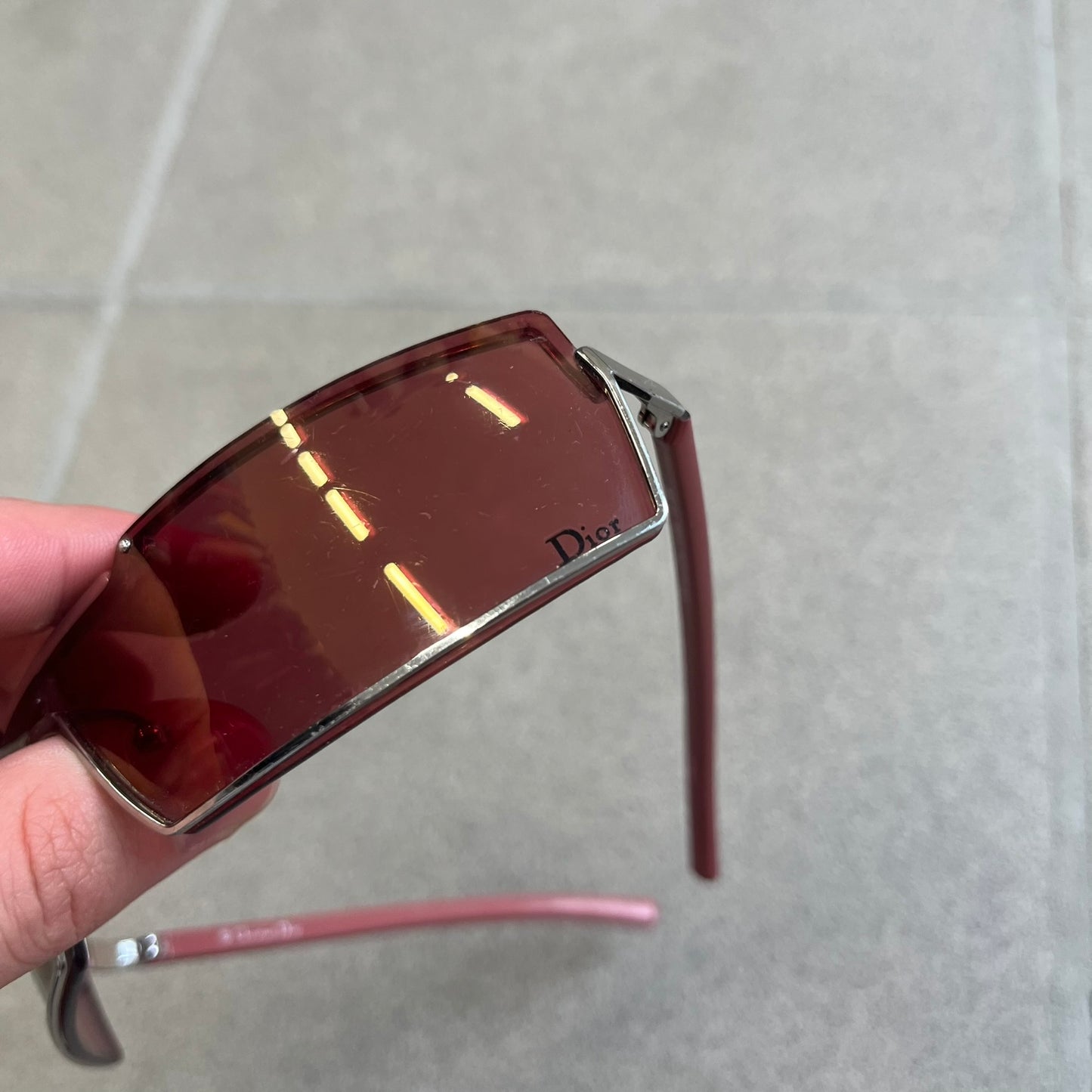 Christian Dior Viktim 2 Pink Sunglasses are an early 2000's eyewear piece from the Safilo era, featuring a futuristic rimless shield silhouette with a sleek wraparound lens design. The sunglasses have a pink/rose tinted lens with subtle Dior logo details at the bottom and minimalist framing. Made in Austria, they come complete with a silver Dior case.