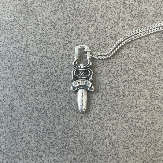 Chrome Hearts Dagger Zipper Pendant crafted from .925 silver, featuring the brand’s signature double-sided dagger design with “Chrome” on the guard and “Hearts” on the blade. Comes on a standard 925 Silver chain (non-CH). Square bail for chain attachment with 925 tag on one side and 89 03 on the other. The dagger was originally a zipper pull.