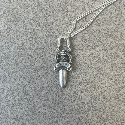Chrome Hearts Dagger Zipper Pendant crafted from .925 silver, featuring the brand’s signature double-sided dagger design with “Chrome” on the guard and “Hearts” on the blade. Comes on a standard 925 Silver chain (non-CH). Square bail for chain attachment with 925 tag on one side and 89 03 on the other. The dagger was originally a zipper pull.