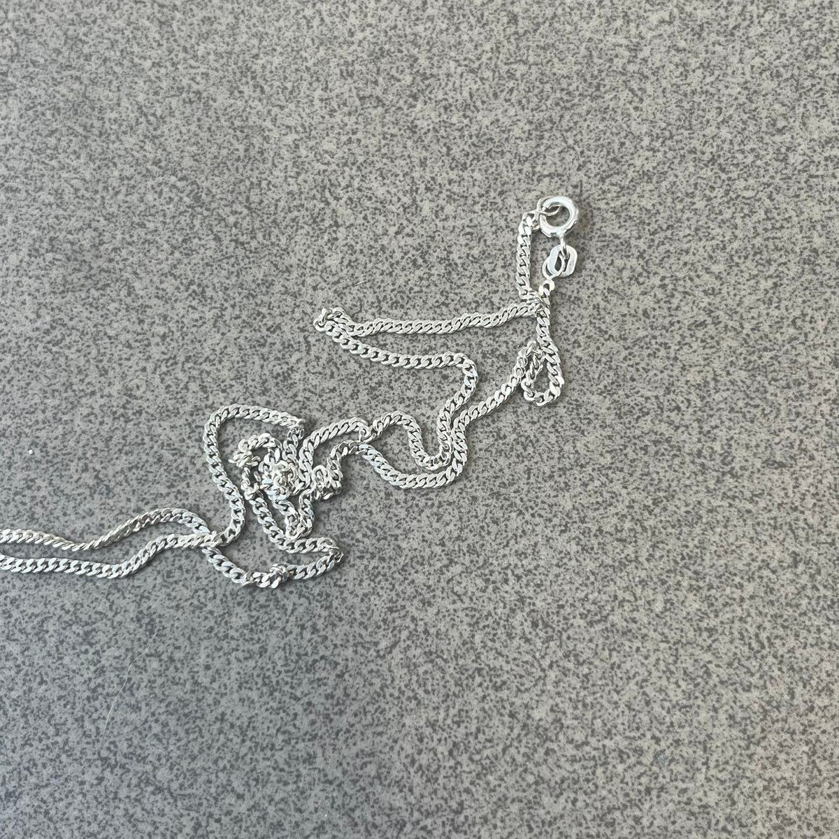 Chrome Hearts Dagger Zipper Pendant crafted from .925 silver, featuring the brand’s signature double-sided dagger design with “Chrome” on the guard and “Hearts” on the blade. Comes on a standard 925 Silver chain (non-CH). Square bail for chain attachment with 925 tag on one side and 89 03 on the other. The dagger was originally a zipper pull.