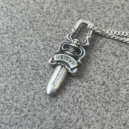Chrome Hearts Dagger Zipper Pendant crafted from .925 silver, featuring the brand’s signature double-sided dagger design with “Chrome” on the guard and “Hearts” on the blade. Comes on a standard 925 Silver chain (non-CH). Square bail for chain attachment with 925 tag on one side and 89 03 on the other. The dagger was originally a zipper pull.